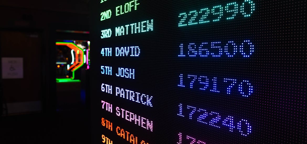 Colorful illuminated arcade scoreboard displaying high scores in a vibrant gaming ambiance.